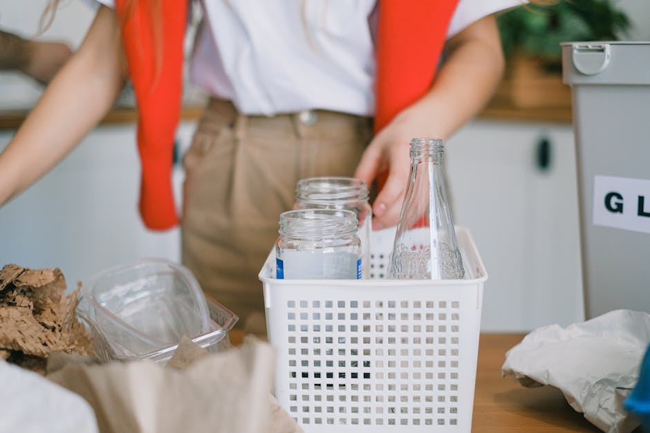 A large pile of mixed household waste and discarded plastics and containers, including bottles, jars, and packaging, spread across an outdoor area. The waste features various colours, predominantly wh